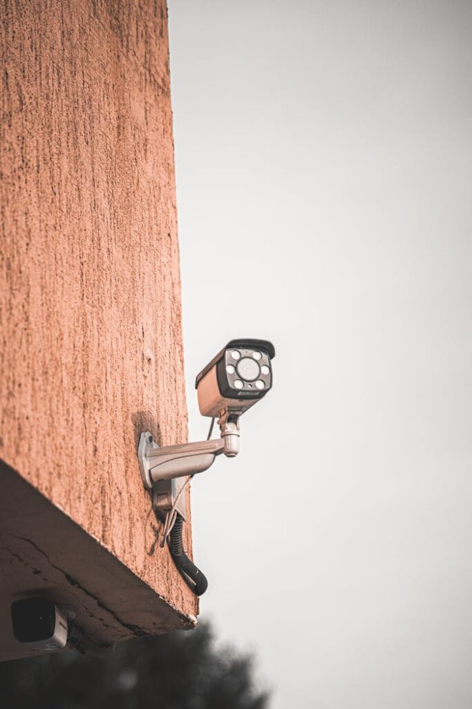 Close-up of a security camera mounted on a building wall, capturing urban safety measures.