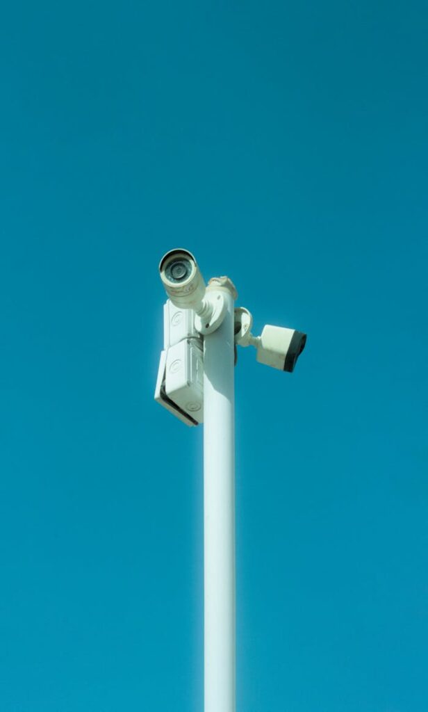 Close-up view of a security camera on a pole under clear blue skies, emphasizing security and technology.